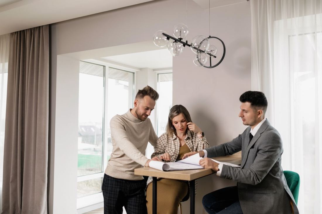 Couple de clients signant un devis à la table de leur salon, face à leur interlocuteur