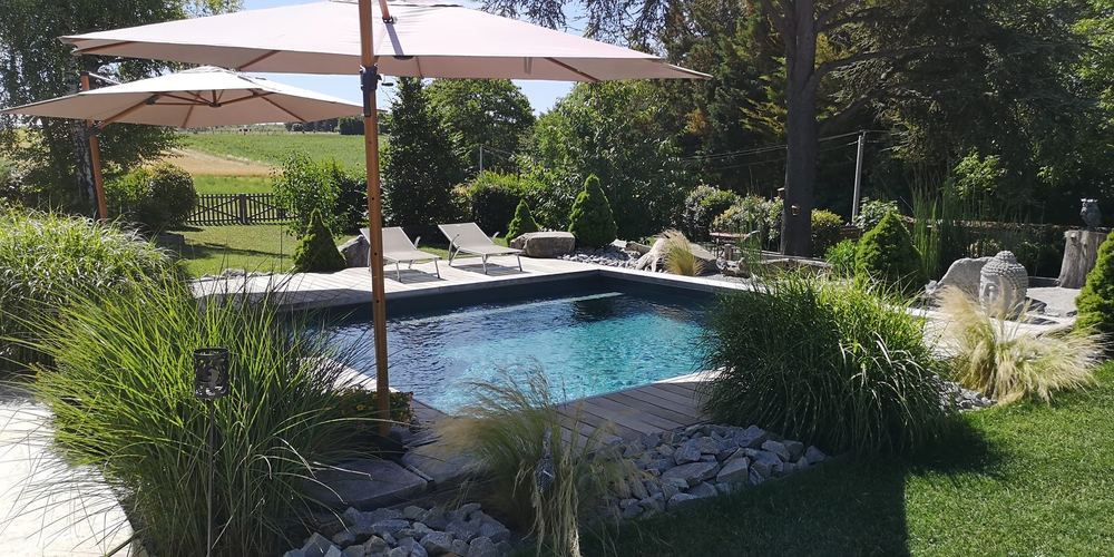 Piscine entourée de massifs et de graminées dans un jardin paysager
